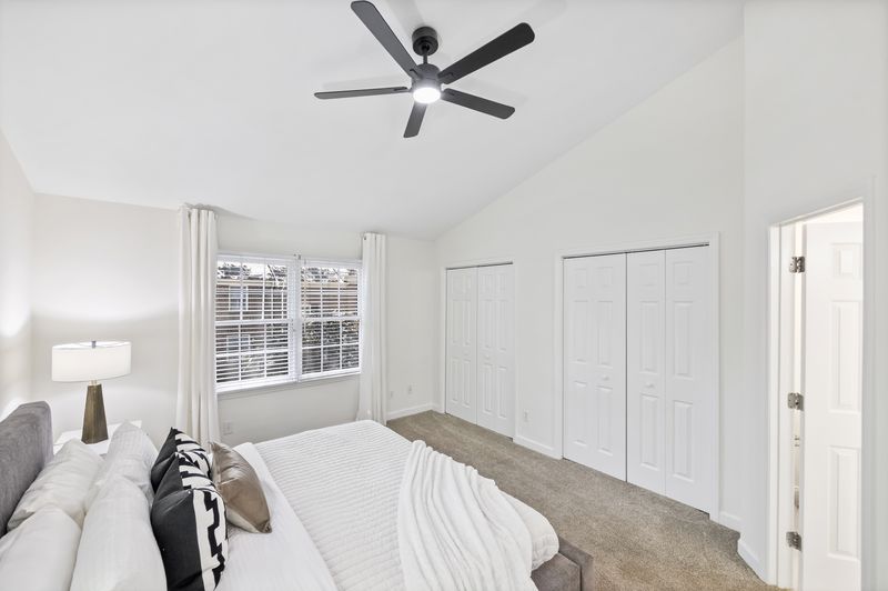Primary bedroom with a vaulted ceiling and dual closets