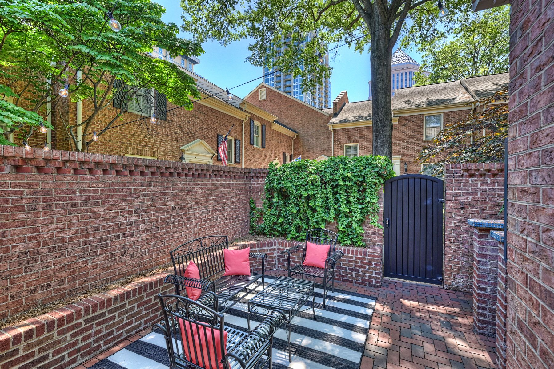 Private brick courtyard with red bistro seating, ivy walls, and the skyline above