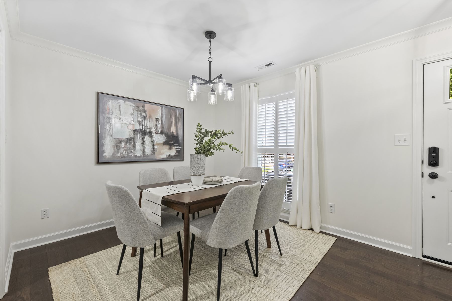 Flexible front room set up for dining, with shuttered windows and dark hardwood floors