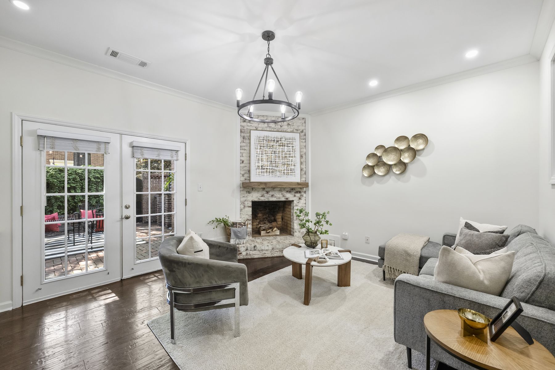 Living room with a limewashed brick fireplace, white built-ins, and French doors to the courtyard