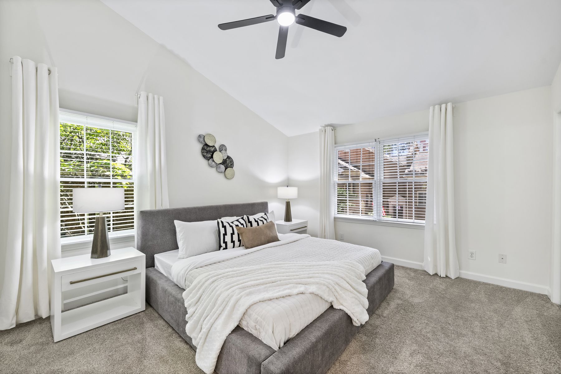 Vaulted primary bedroom with dual closets and two shuttered windows